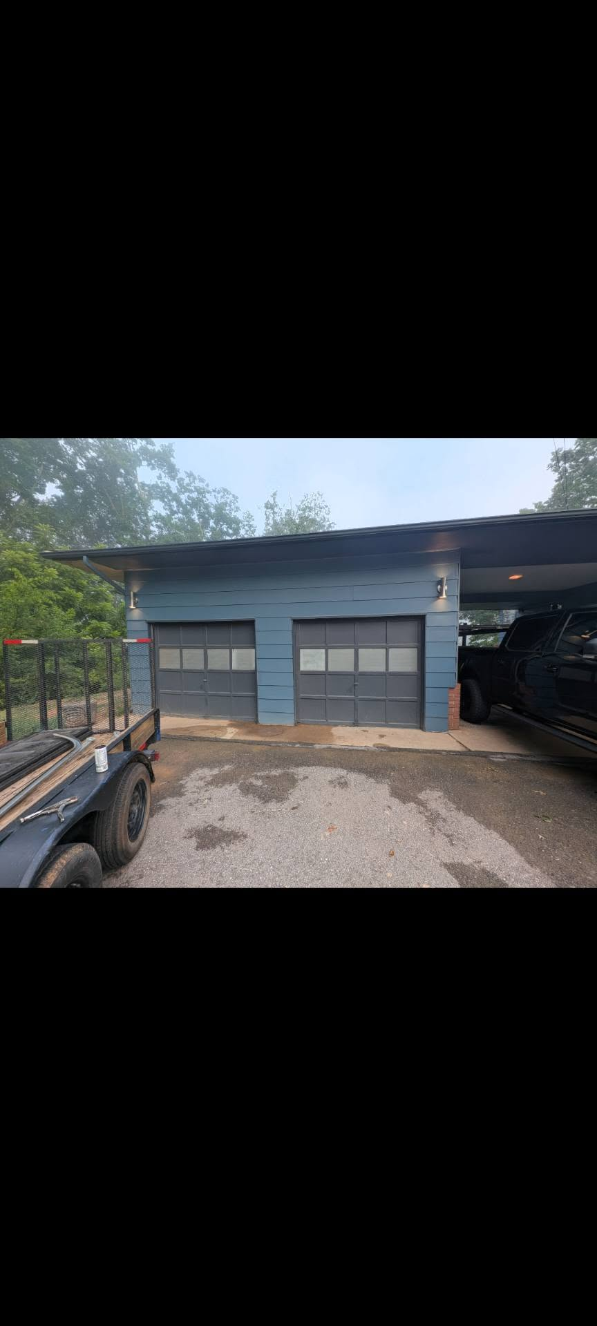 Two matching gray garage doors installed on blue home