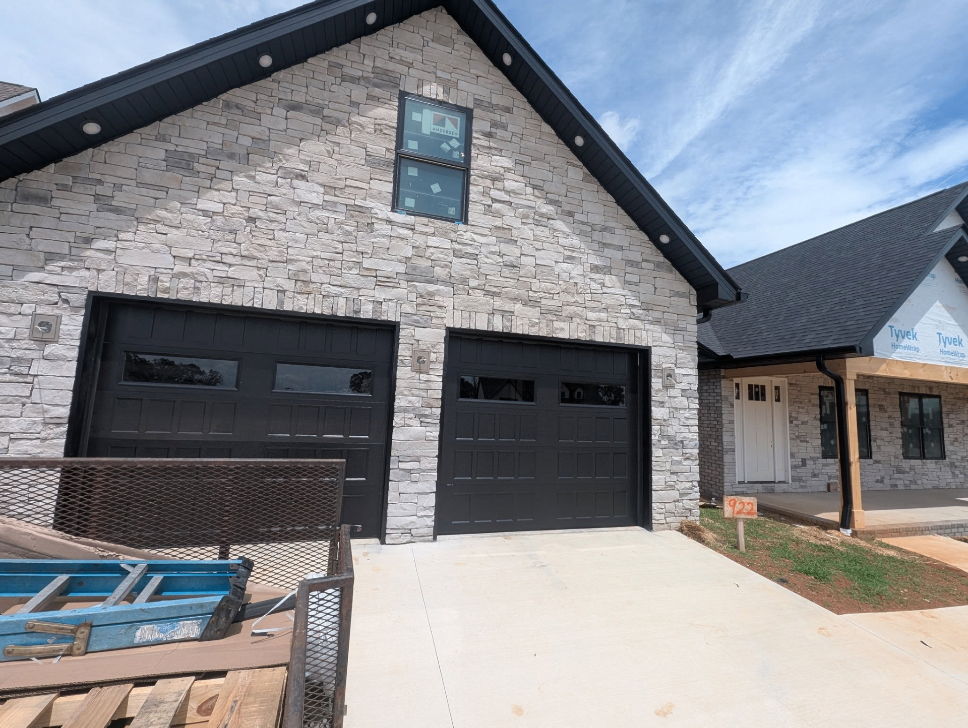 Two black garage doors on stone-front new construction home